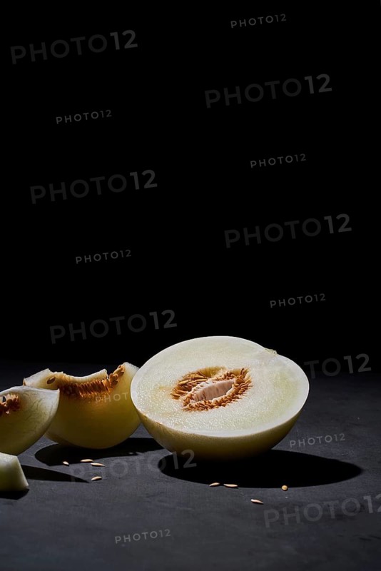 Side view of a fresh melon cut in half on black background