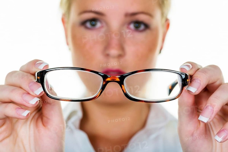 A blonde woman gets new glasses, symbolic photo for poor vision and defective vision, dioptre selection, cash register frame studio photo, Austria