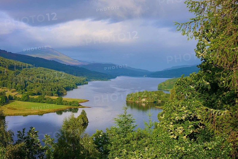 The sun's rays hit a river flanked by wooded hills, Queens View, Fincastle, Pitlochry, Scotland, United Kingdom, Great Britain