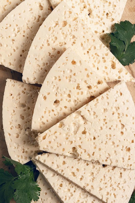 Sliced Georgian cheese, factory grade, on a wooden board, top view