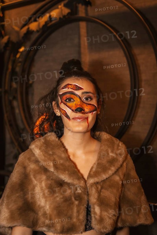Halloween party with friends in a disco nightclub, portrait of a woman with a painted face with red wounds