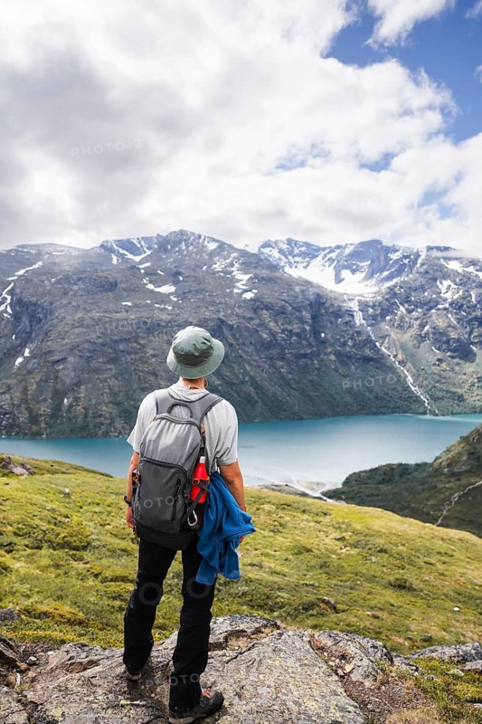 A traveler in rugged terrain admires Norway's majestic landscape The image captures the essence of outdoor adventure, trekking, and camping amid stunning natural beauty