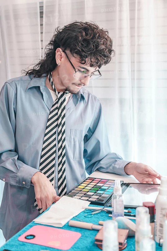 Young make-up artist carefully arranging cosmetics and tools on table, preparing for client session in bright, professional setting, showcasing diversity and inclusion in beauty industry