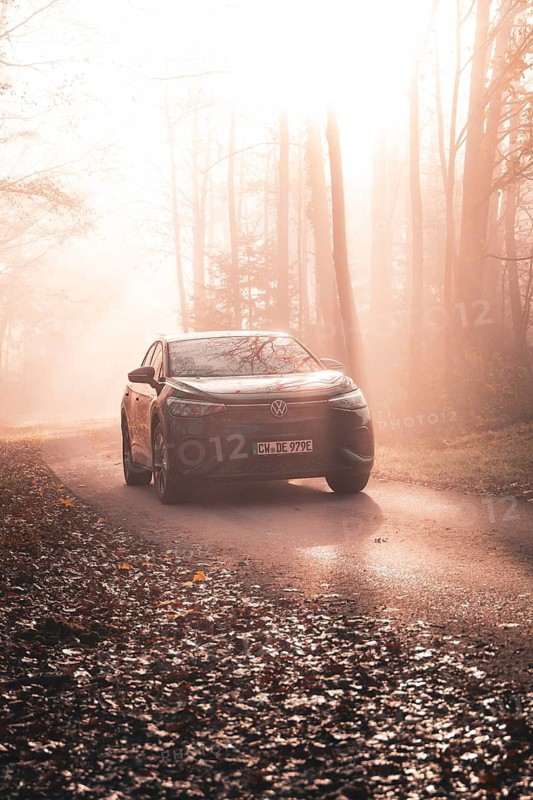 In fog and bright sunlight, a car stands on an autumnal forest road, electric car VW ID5, Deer Carsharing, Gechingen, Black Forest, Germany