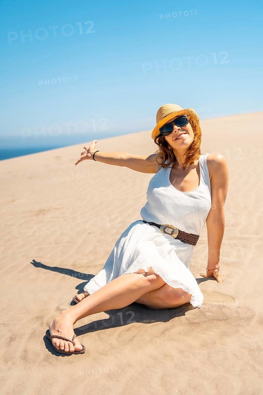 Vertical photo of a woman showing an idyllic coastal landscape sitting on the sand in Cabo de Gata, Spain