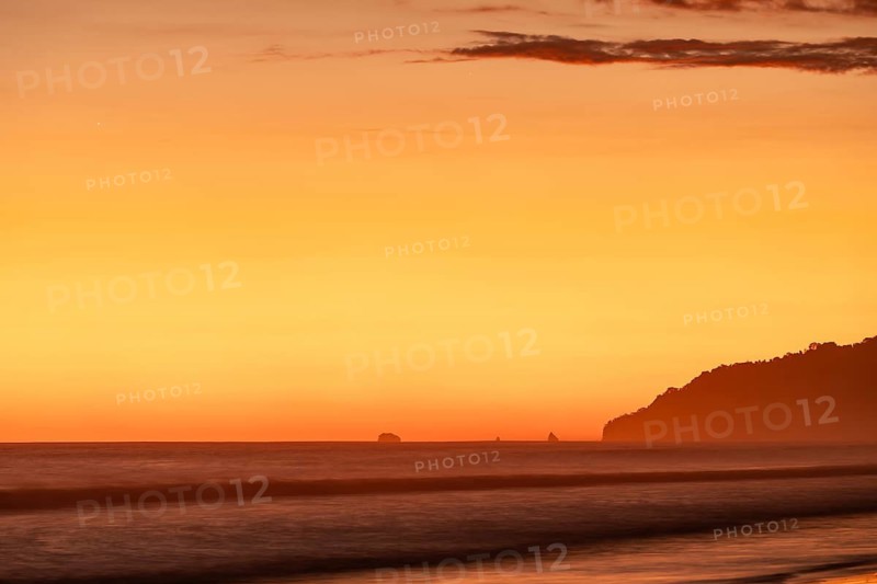 After sunset, the deep red sky glows above palms and ocean spray with views of Corcovado National Park. Costa Rica