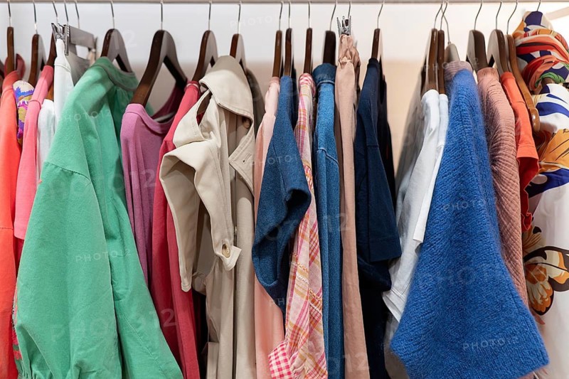 A vibrant racks displays various clothing styles, from casual to formal, in diverse colors and fabrics. Each piece is neatly hung, creating a visually appealing look in the clothes shop