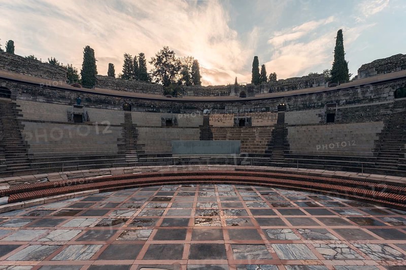 The image captures the grandeur of the ancient Roman theatre in Merida, Badajoz, Spain. This iconic structure showcases impressive stonework and historical significance at dusk
