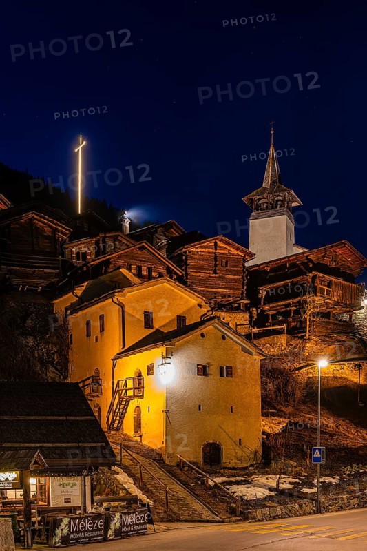 Old farmhouses and barn barn, white cellars, the illuminated cross and the illuminated church tower of the Saint Theodule church, night view, historic town center, Grimentz, Val d'Anniviers, Valais Alps, Canton of Valais, Switzerland