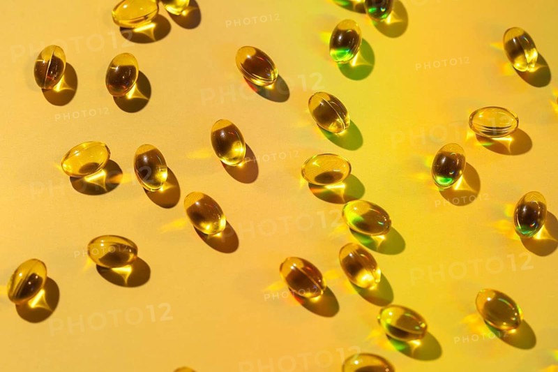 A collection of glossy softgel capsules scattered on a vibrant surface, highlighting their use as health supplements. Ideal for promoting vitamin intake for a balanced lifestyle