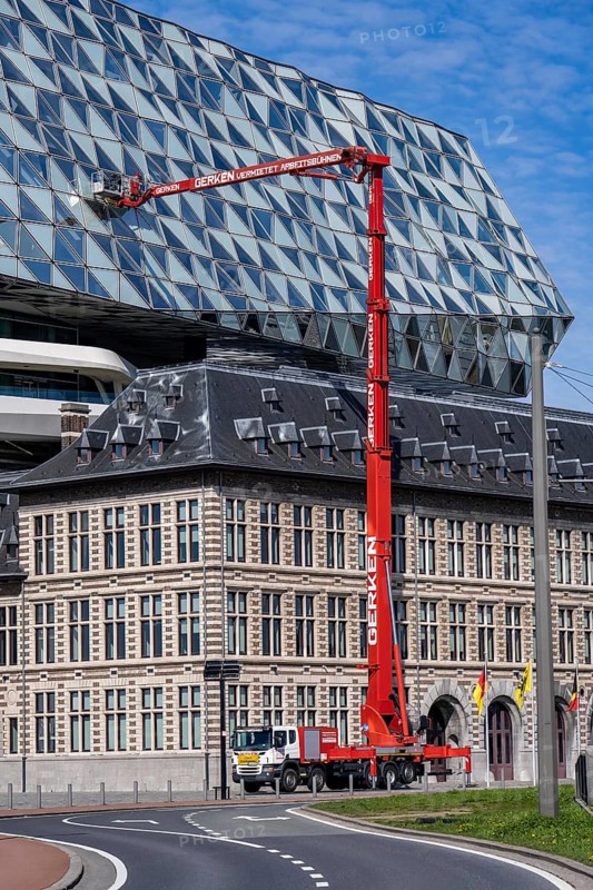 The Antwerp Port Authority building, Havenhuis, former fire brigade barracks in the harbour, renovated and with an attached glass structure, in the shape of a ship's hull, administrative headquarters of the Antwerp Port Authority, designed by Zaha Hadid, building cleaners clean the windows, truck work platform of the German rental company Gerken, Antwerp, Flanders, Belgium