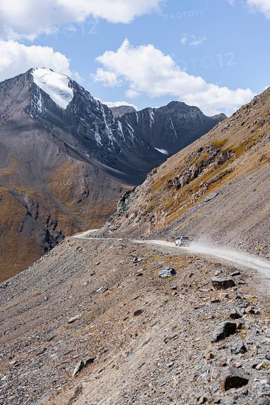 Narrow gravel track in mountain landscape at Chong Ashuu Pass, Tian Shan Mountains, Issyk-Kul, Kyrgyzstan