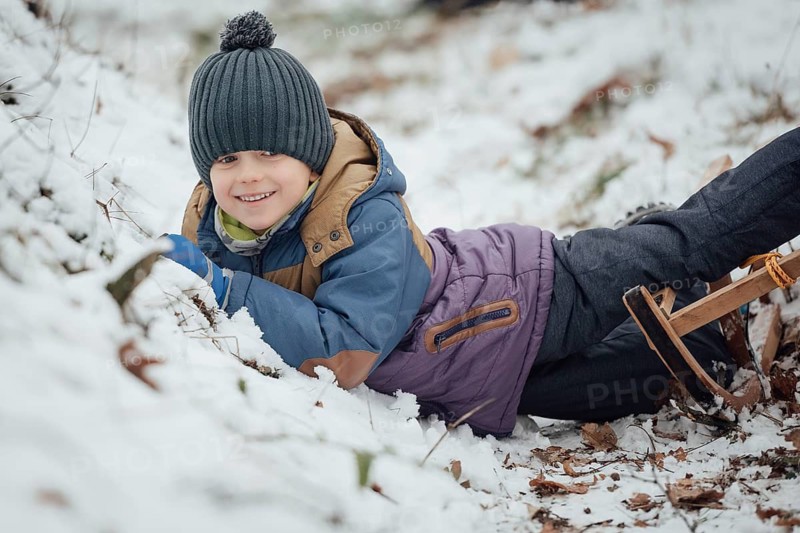 Six year old boy smiling after fall down from the sled.
