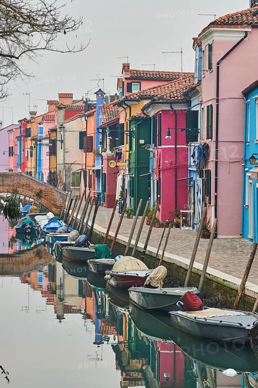 Colorful houses beside the waterway at 'Fondamenta di Terranova' with boats lying in the water on the island of Burano, Italy