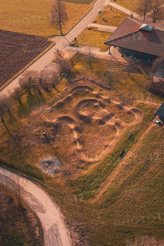 Aerial view of a mound with winding paths surrounded by country road and autumn landscape, bike park, Gechingen, Calw district, Germany