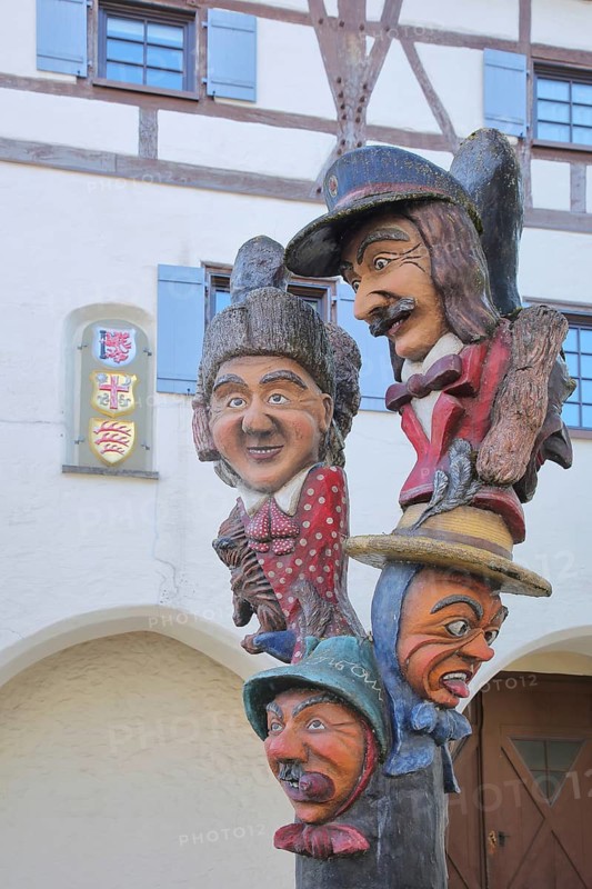 Fool's fountain by Egon Leeuw 1989 in front of the Buchauer, Amtshaus with coat of arms, carnival fountain, four fools, faces, Swabian-Alemannic, Fasnet, fountain, carnival, Bad Saulgau, Upper Swabia, Swabia, Baden-Württemberg, Germany