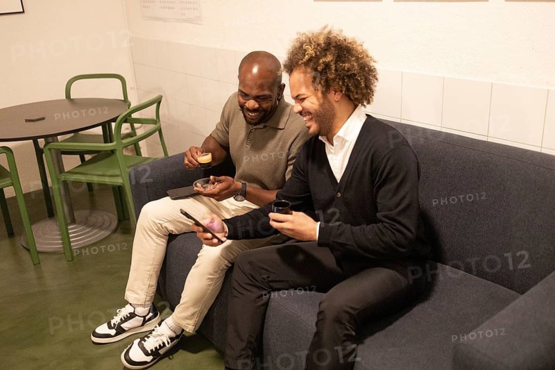 Two colleagues enjoying coffee and conversation in a modern coworking space in Barcelona, fostering creativity and collaboration in a relaxed and friendly environment