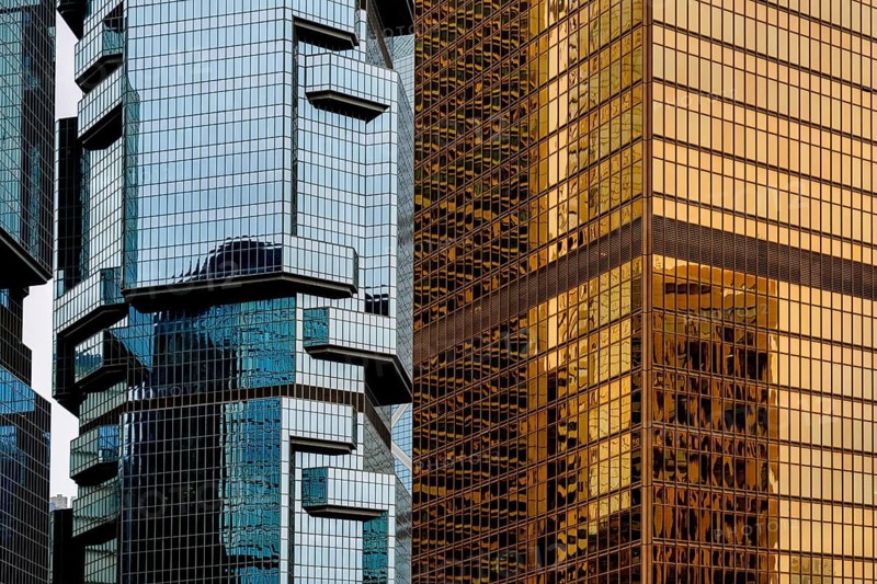 Contrast between modern architectural designs in the Hong Kong skyline, capturing the interplay of glass, steel, and reflective surfaces under sunlight