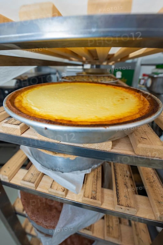 Freshly baked cheesecake in a tray on a wooden shelf in a bakery