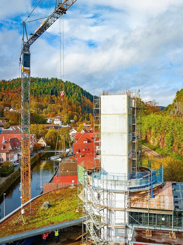 Construction of a tall building with crane in autumnal landscape, surrounded by nature and city, ZOB Calw conversion for Hermann Hessebahn, Calw, Black Forest, Germany