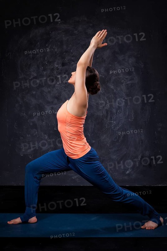 Beautiful sporty fit yogini woman practices yoga asana Virabhadrasana 1, warrior pose 1