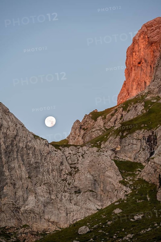 Moon behind rocky peaks at sunrise, alpenglow, Carnic High Trail, Carnic Main Ridge, Carnic Alps, Carinthia, Austria