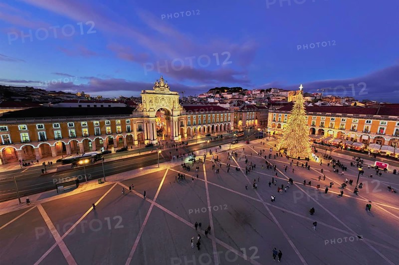 Praca do Comercio shines with a large illuminated Christmas tree and vibrant decorations, as crowds gather during winter twilight in Lisbon
