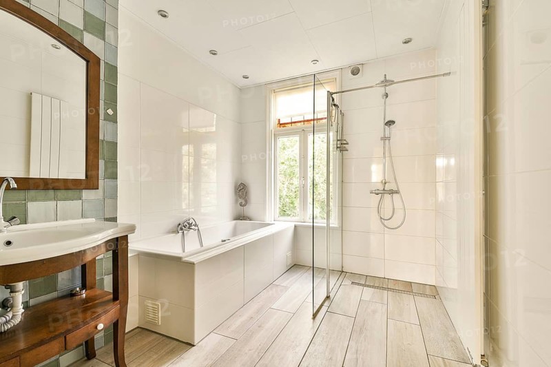 Features a sleek design with dual fixtures, natural lighting from a window, and a clean, tiled aesthetic that enhances relaxation