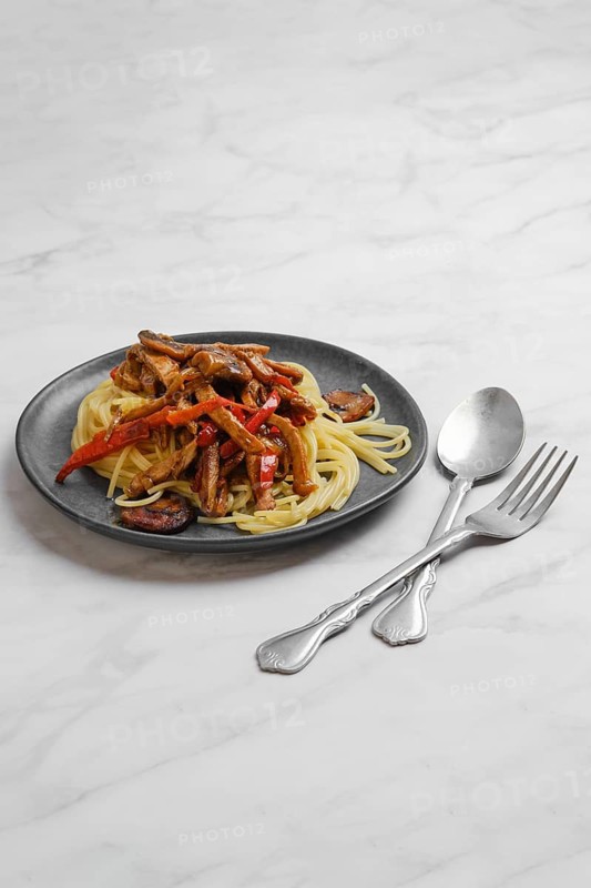 Plate with spaghetti with mushrooms and pork in sticky sauce