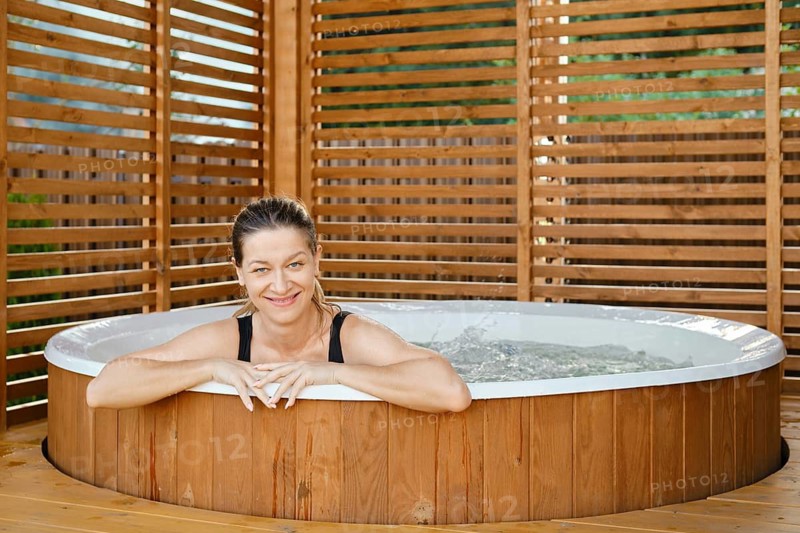 Happy woman in outdoor hot tub. Woman in an open air jacuzzi
