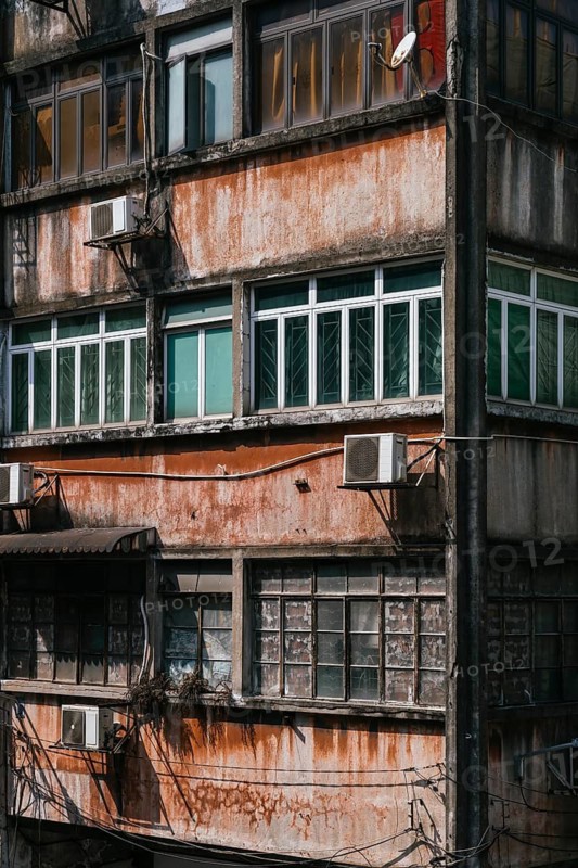 Close-up of an aged building facade featuring barred balconies and windows for security and protection against typhoons, captured in the urban context of Macau