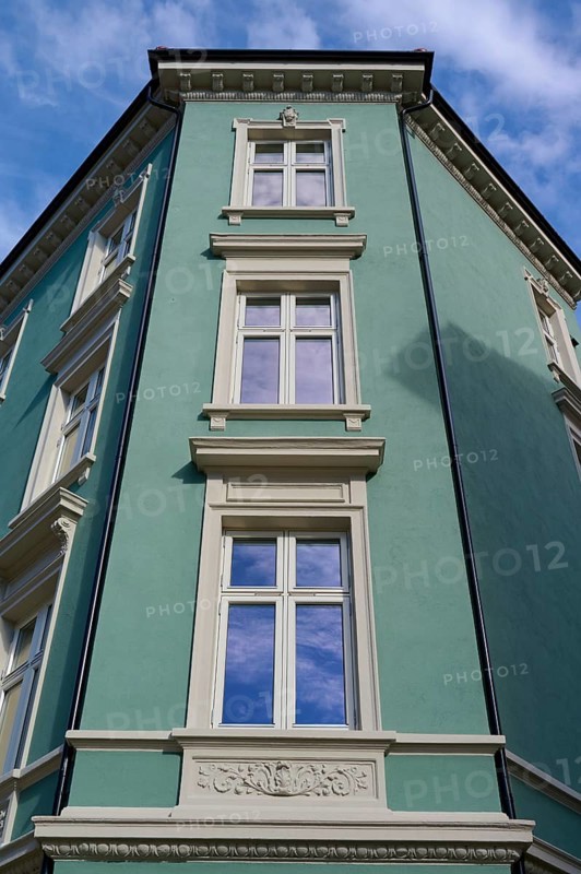 Historic building with mint facade and cream-coloured window frames under a clear blue sky with light clouds, Bergen, Vestland, Norway