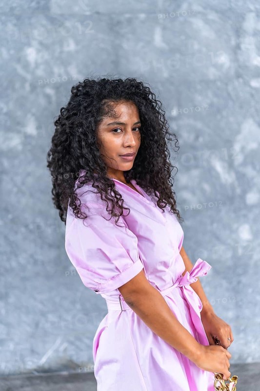 Vertical portrait of a confident latin female model posing with purse and pink attire