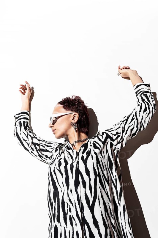 A fashion model exudes confidence wearing an eye-catching zebra animal print top. Captured using flash photography in a studio setting, the image highlights modern style