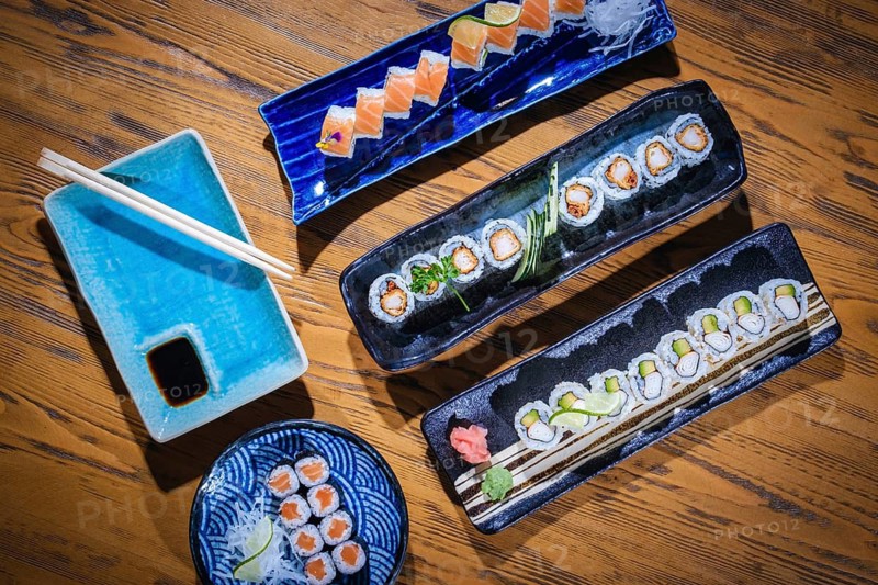 Overhead view of various sushi rolls beautifully arranged on ceramic plates, ready to be savored