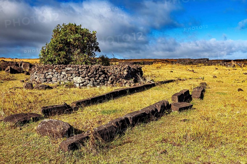Ancient stone construction on a grassy field under a blue sky, The ruins on Easter Island in the Pacific Ocean