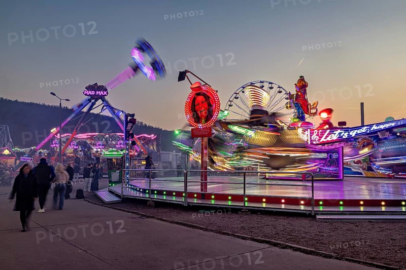 Colourful rides and lights illuminate the fair at dusk and full of movement, carousel and hustle and bustle of summer winnings in Eisenach