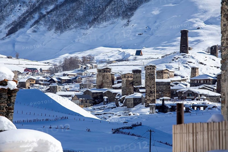 A picturesque mountain village with ancient stone towers blanketed in snow in Georgia The serene winter landscape captures the essence of remote, historical architecture