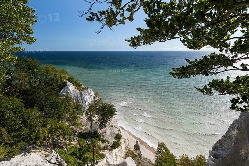White chalk cliffs at Hundevængsfald with milky water from chalk sediment by the stormy Baltic Sea under a blue sky. Møns Klint, Sjælland, Denmark