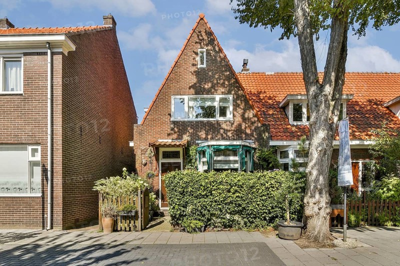 A picturesque house featuring a gabled roof, vibrant greenery, and a welcoming front yard, set against a clear blue sky