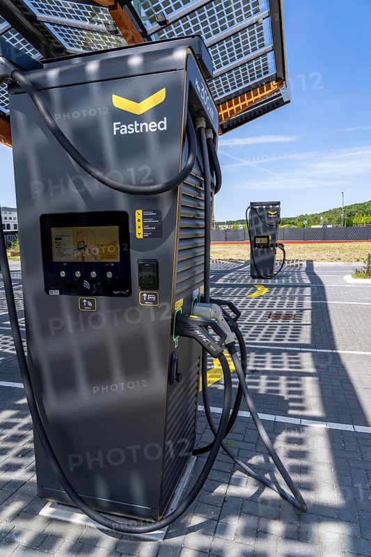 Electric charging station on the site of the former Lohberg colliery in Dinslaken, operated by Fastned, uses electricity from wind power and solar energy, fast-charging columns, with its own solar roof, in the background the 11, 500 square metre solar roof on the colliery's former coal mixing hall, wind farm on the Lohberg slagheap, North Rhine-Westphalia, Germany