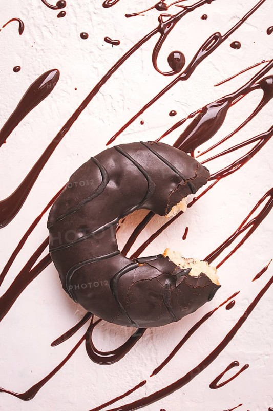 Donuts, in chocolate glaze, on a beige background, with liquid chocolate