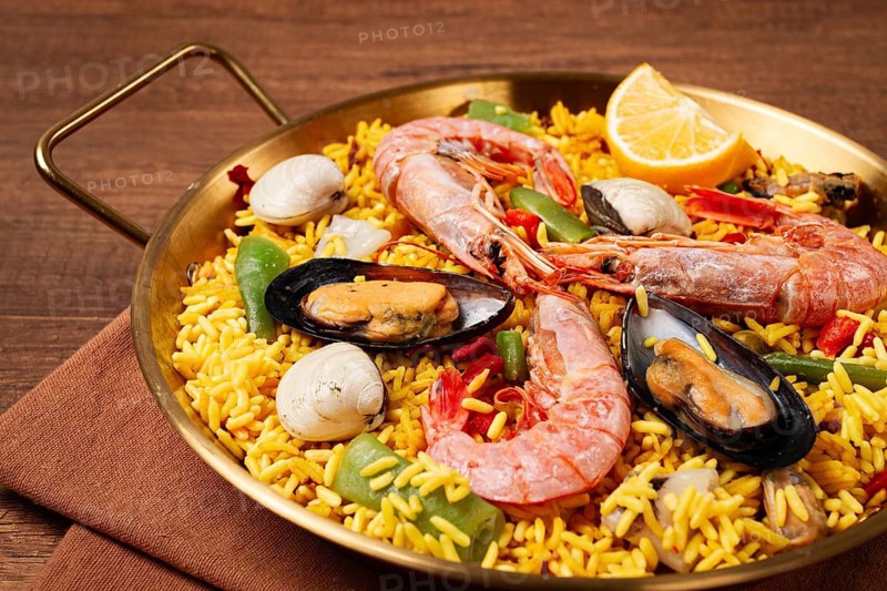 Seafood paella, in a frying pan, on a wooden table, no people