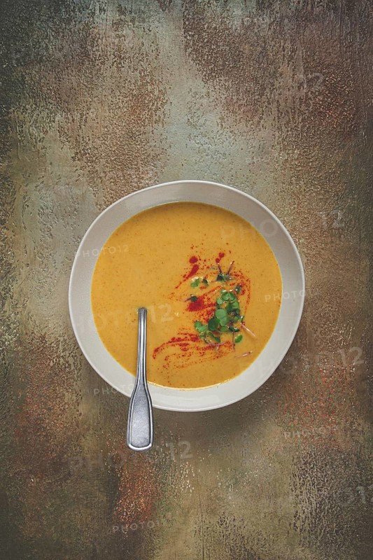 Pumpkin cream soup, in a white bowl on a textured background, top view, homemade, no people, rustic style