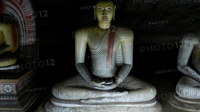 Seated Buddha statue in deep meditation surrounded by darkness, Dambulla cave temple, Sri Lanka