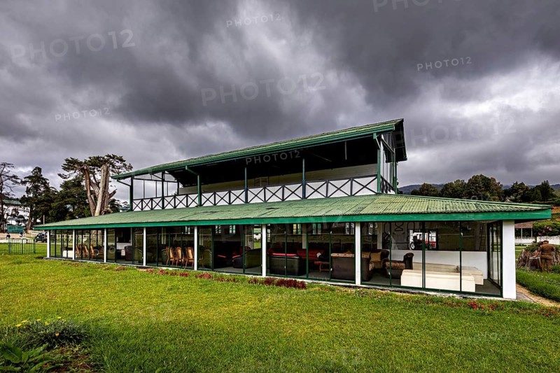 Modern building with large areas of glass and green roof against a cloudy sky, The Nuwara Eliya Sri Lanka Racecourse
