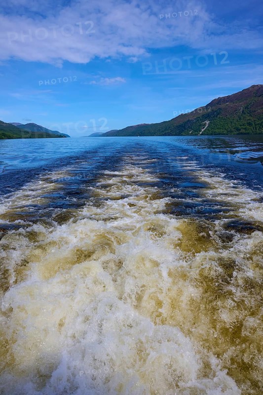 Calm lake with waves and surrounding mountains under blue sky, Fort Augustus, Loch Ness, Scotland, United Kingdom, Great Britain