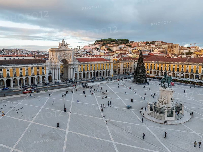 Beautiful winter sunset over Praca do Comercio featuring the Arco da Rua Augusta and a decorated Christmas tree surrounded by people. Lisbon, Portugal