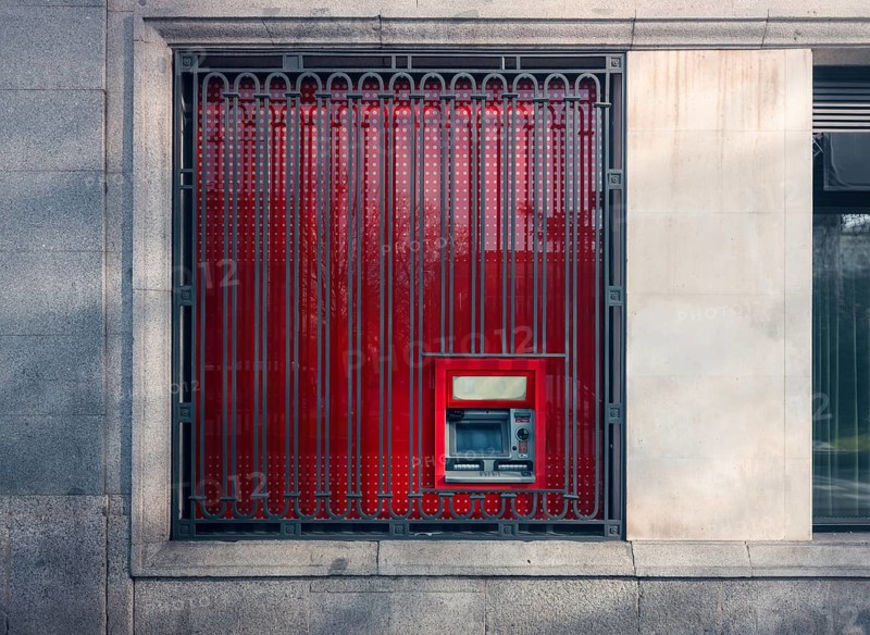 A striking image capturing a red ATM machine securely located behind ornate, patterned iron bars on a building in Colon City, Panama, blending modern banking with traditional security