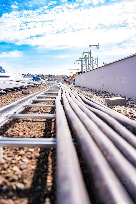 Several pipes run across a roof covered with pebbles under a blue sky, PV assembly. OBI Baumarkt, Mühlacker, Enzkreis, Germany
